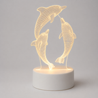 A 3D optical illusion LED night light featuring two dancing dolphins in a wireframe design, illuminated from within on a round white base against a neutral gray background.