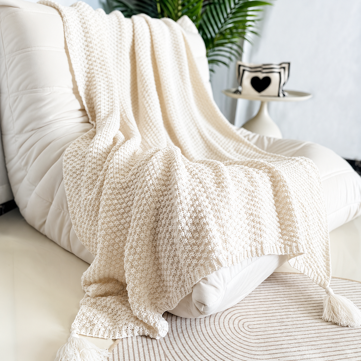 Beige acrylic knit throw blanket with a pebbled stripe texture draped over a cream chair