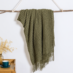 Olive textured acrylic knit throw blanket hanging over a branch