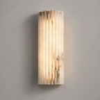 Vertical wall sconce with a softly glowing textured shade mounted on a light gray wall.