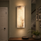 Vertical wall sconce glowing beside a doorway in a warmly lit interior.