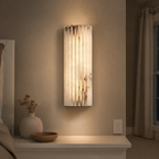 Vertical wall sconce illuminating a recessed wall niche with neutral decor.