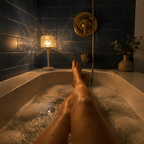 Ambient night light glowing beside a bathtub in a navy tiled bathroom