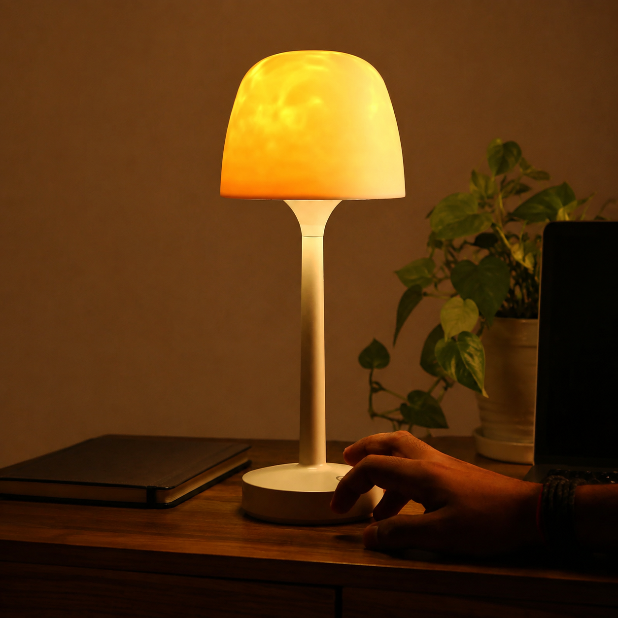 Ambient night light on a walnut desk with a hand touching the base