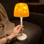 Ambient night light held by its stem beside a charcoal sectional