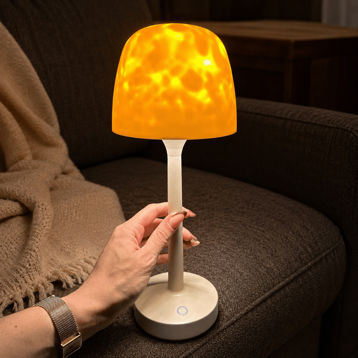 Ambient night light held by its stem beside a charcoal sectional