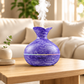 Marbled purple aroma diffuser with a flared neck releasing mist on a wooden table