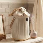Beige towel warmer bucket on a bathroom counter with its lid open
