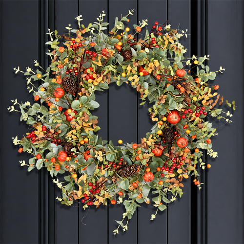 Artificial autumn wreath with small pumpkins berries and green foliage hanging on a dark door