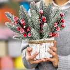 Person holding a planter arrangement of snowy artificial cedar and berry sprigs
