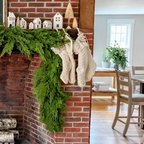 Artificial cedar garland on a brick fireplace mantel shown with separate stocking styling