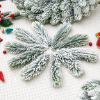 Snow flocked artificial cedar sprigs arranged with seasonal craft props