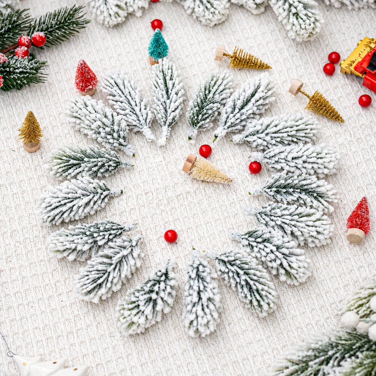 Snowy artificial cedar sprigs arranged in a circle with decorative craft props