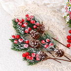 Artificial red berry sprigs laid on fabric showing snowy foliage and pinecone detail