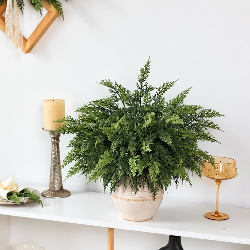 Artificial green cedar sprigs in a separate vase on a console table