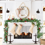 Artificial Christmas garland arranged around a fireplace with knitted stockings.