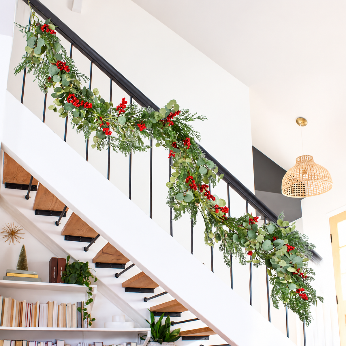 Artificial Christmas garland hanging along a dark stair handrail.