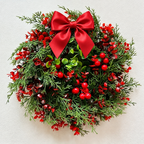 Artificial red berry Christmas wreath with bow shown close up