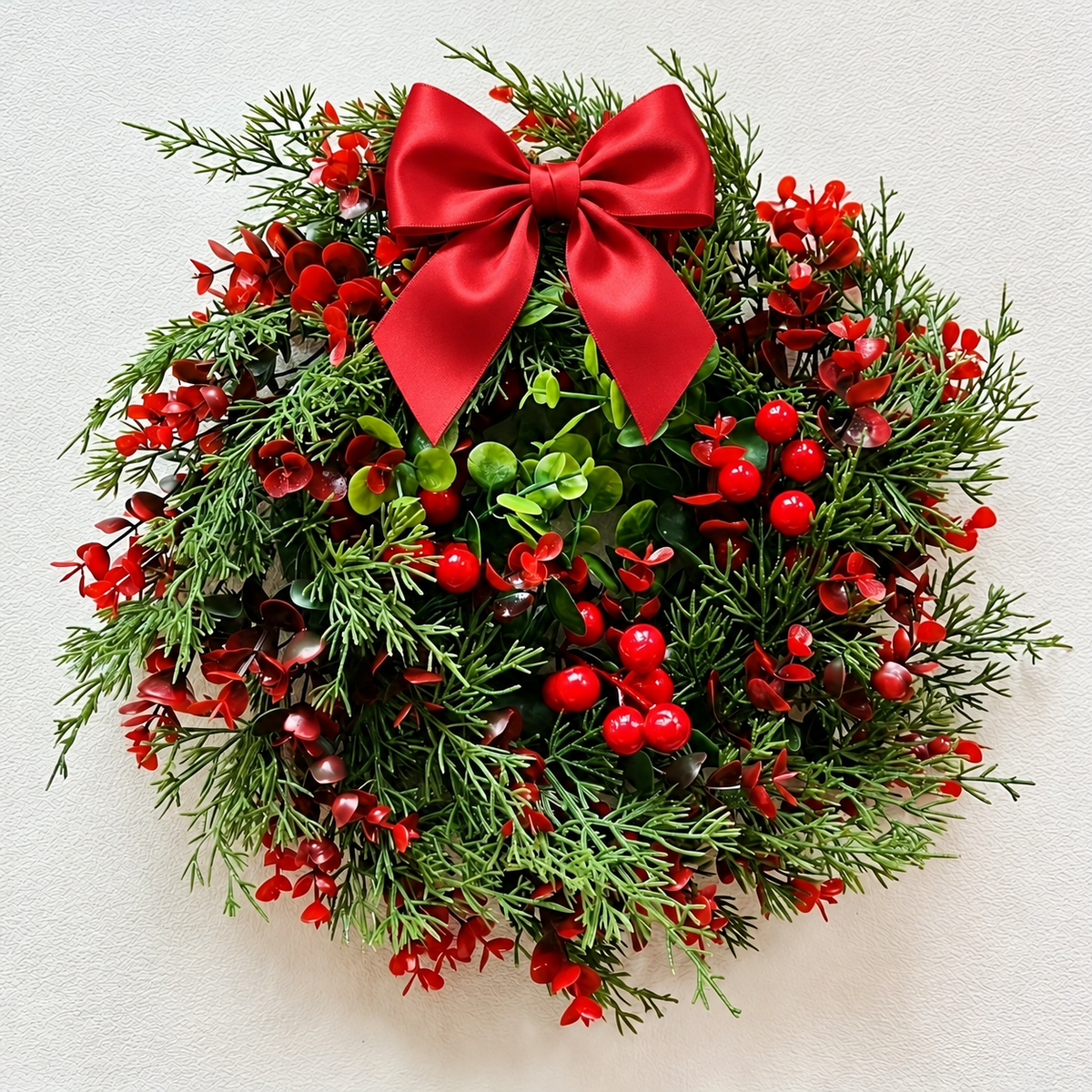 Artificial red berry Christmas wreath with bow shown close up