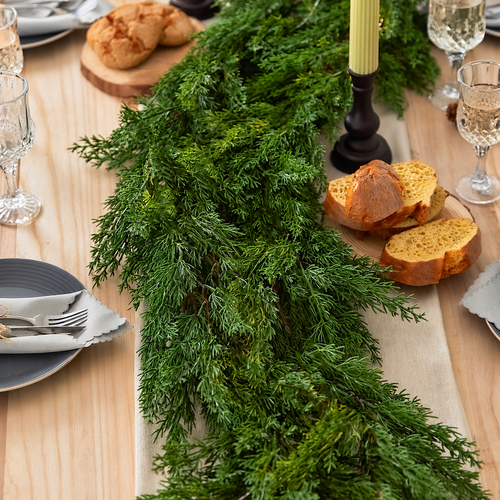 Artificial cypress garland styled down the center of a dining table