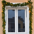 Artificial green cypress garland around a doorway shown with separate decorative lights