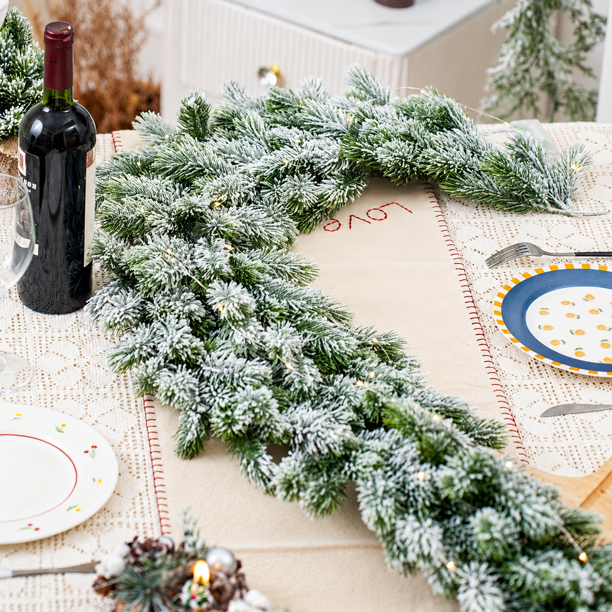 Snow flocked artificial evergreen garland arranged along a dining table