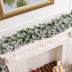 Snow flocked artificial evergreen garland on a white mantel viewed from above