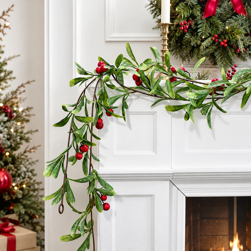 Artificial green mistletoe garland with red berries draped across a festive fireplace