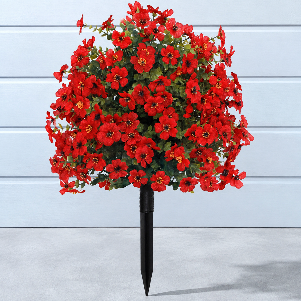 Red artificial outdoor flowers against pale blue panels and concrete