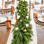 Artificial pine garland styled along a dining table with separate candle and ornament accessories