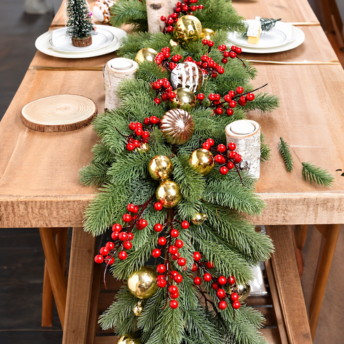 Artificial pine garland on a table shown with separate red berry and bauble styling