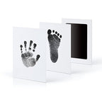 Baby handprint kit with black hand and foot impressions on white cards