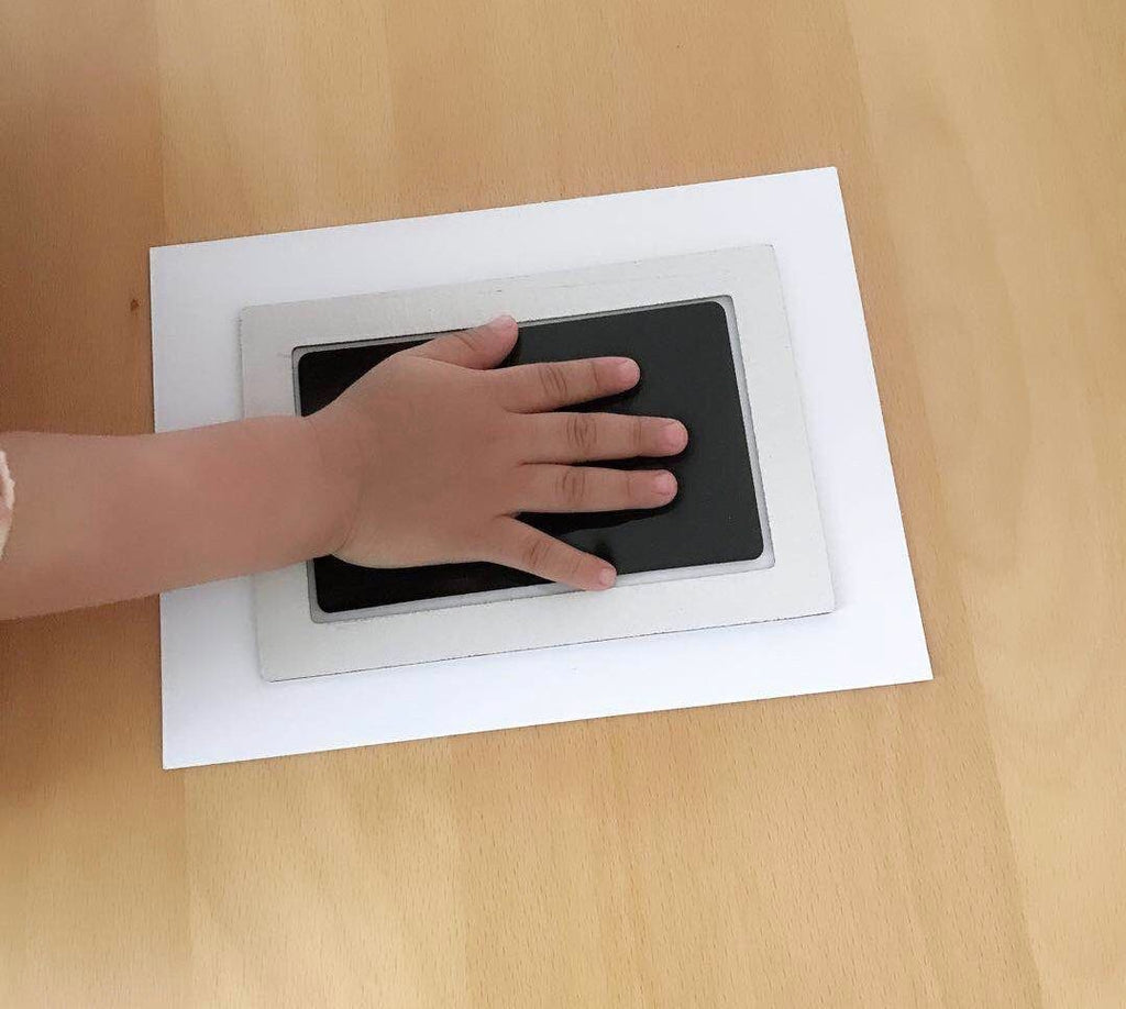 Baby handprint kit with a hand resting on the transfer film
