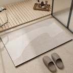 Beige quick dry bath mat with an abstract pattern beside a glass shower.