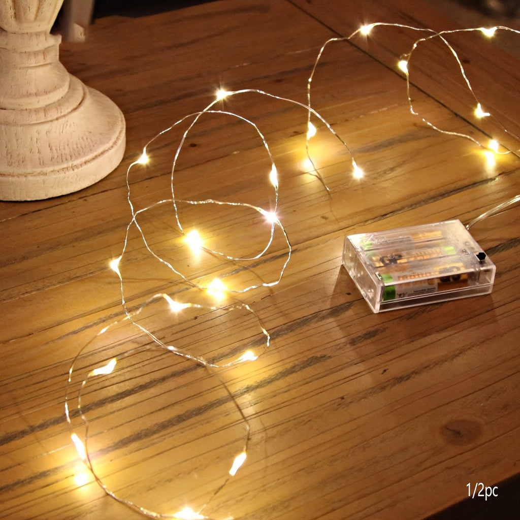 Warm white fairy string lights with a battery box on a wooden table