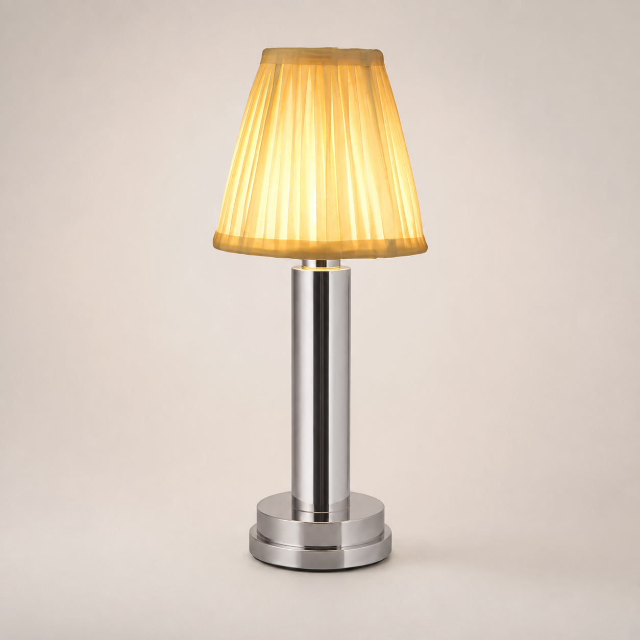 Silver table lamp with a pleated cream shade and silver-tone cylindrical base on a plain background.