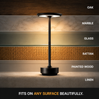 Black table lamp displayed against marble, glass, rattan, painted wood, and linen surface samples.