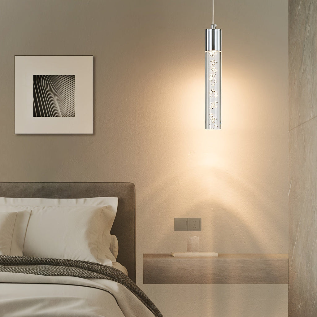 Single silver mini pendant with a clear bubble acrylic cylinder beside a bed