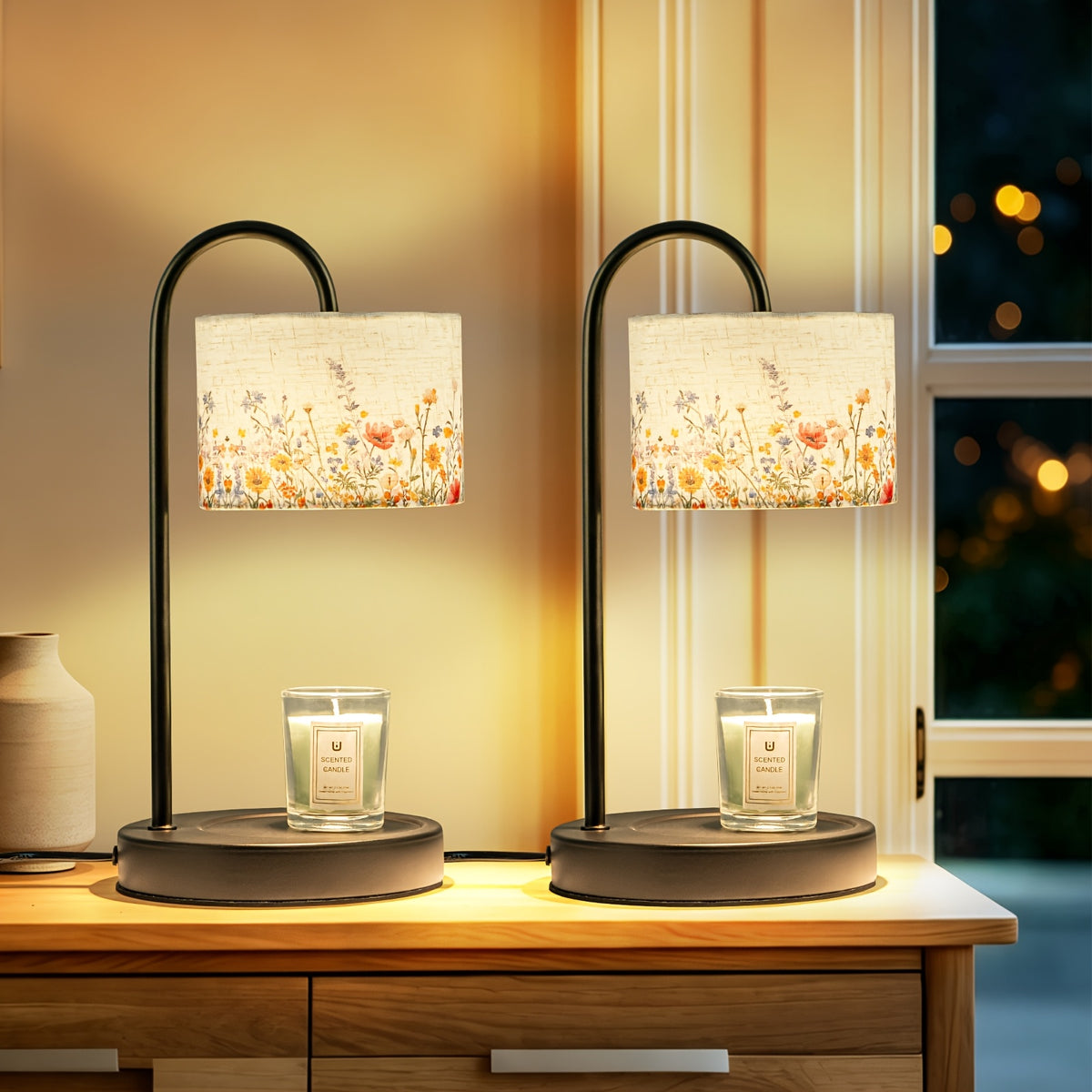 Two floral shade candle warmer lamps on a table near a window.