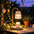 Candle warmer lamp glowing on a table beside plants and flowers.