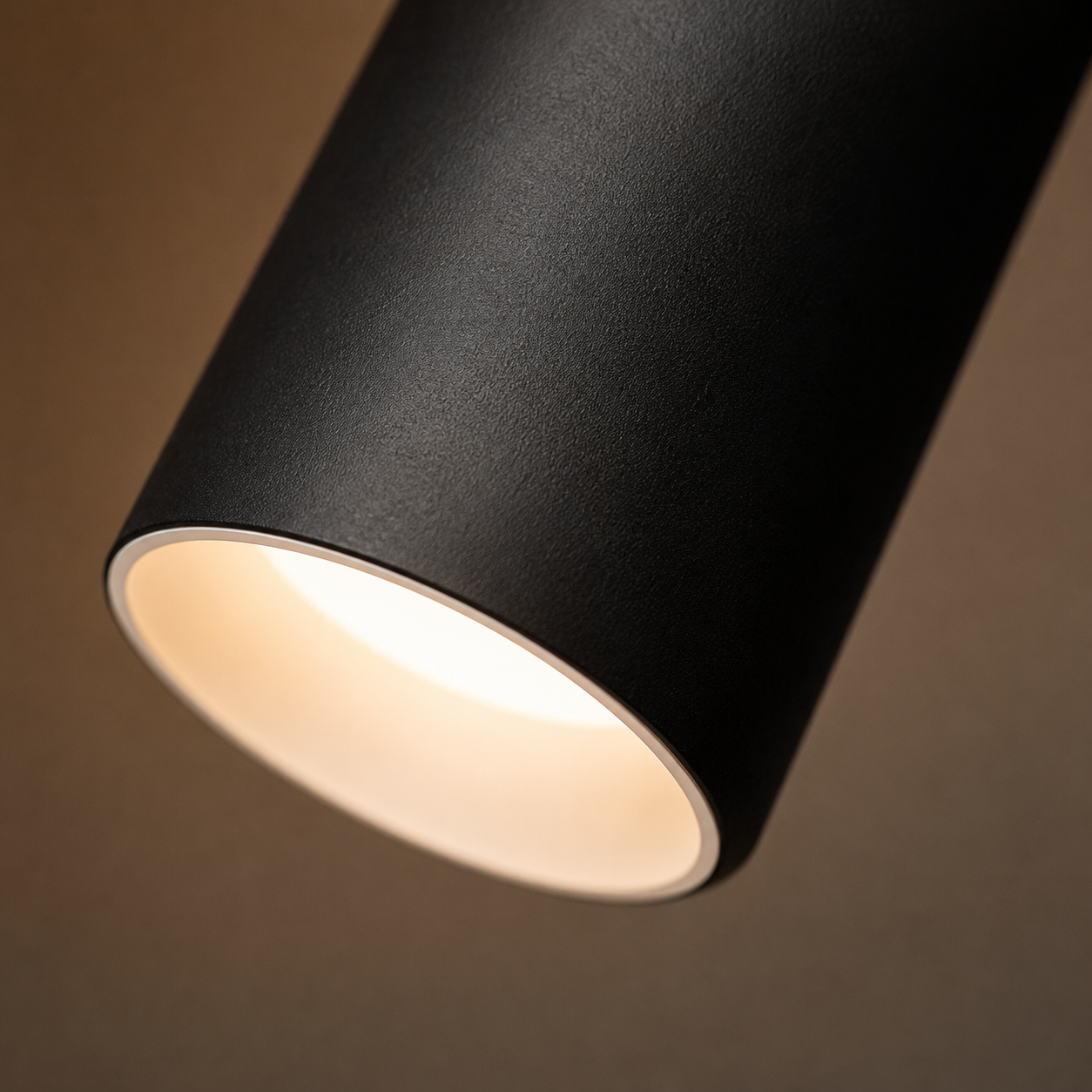 Close-up of a black ceiling spotlight with a softly glowing circular opening.