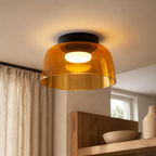 Orange smoked glass ceiling light glowing above a modern wood shelf.