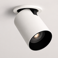 White adjustable cylindrical LED ceiling spotlight with a black interior, glowing warm white against a neutral ceiling.
