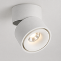 Hand adjusting round LED ceiling spotlight glowing warm white. 