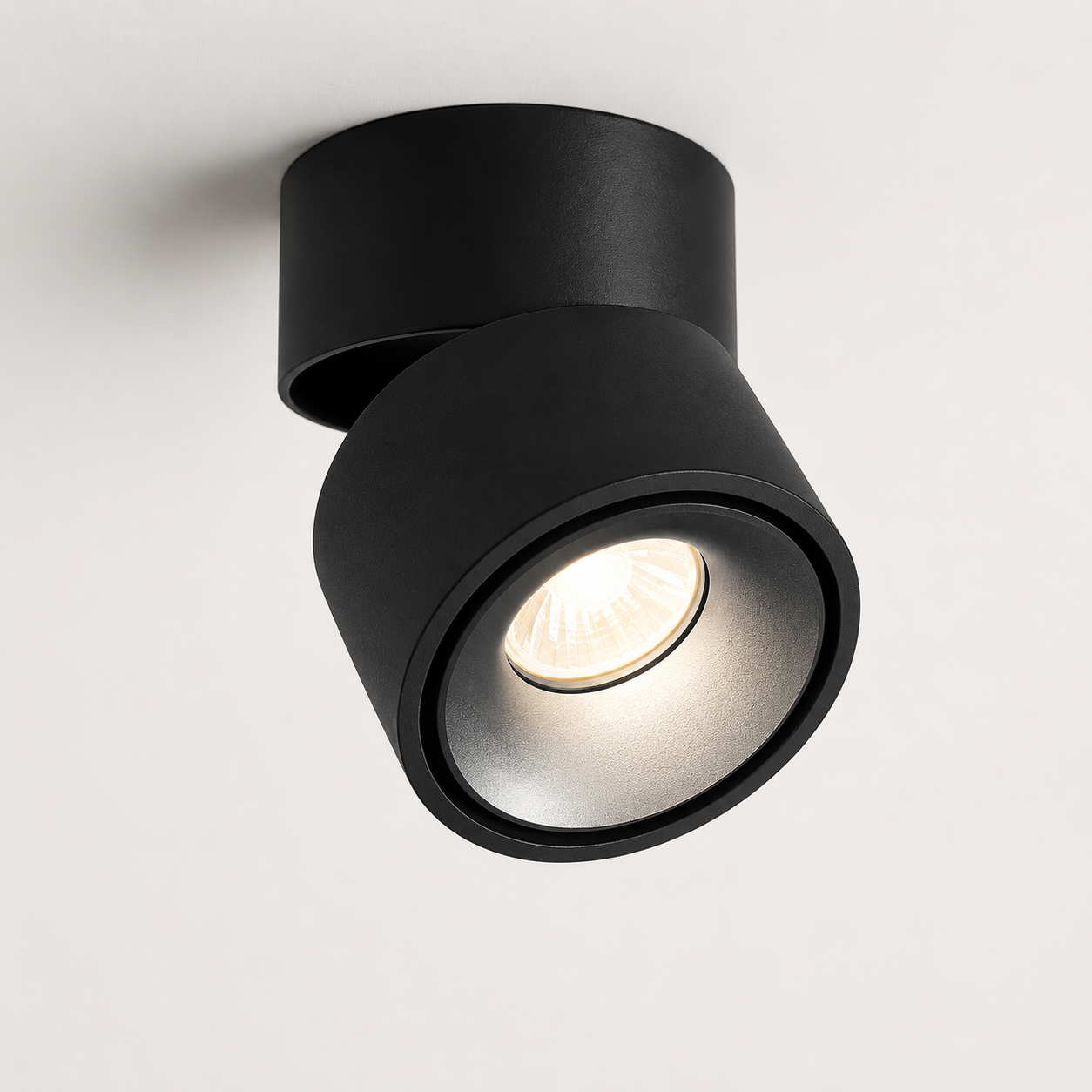 Hand adjusting round LED ceiling spotlight glowing warm white. 