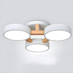 White ceiling light with three round shades and wood details.