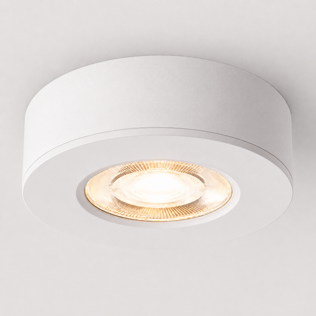 White ultra-thin round LED ceiling spotlight glowing warm white on a white ceiling.