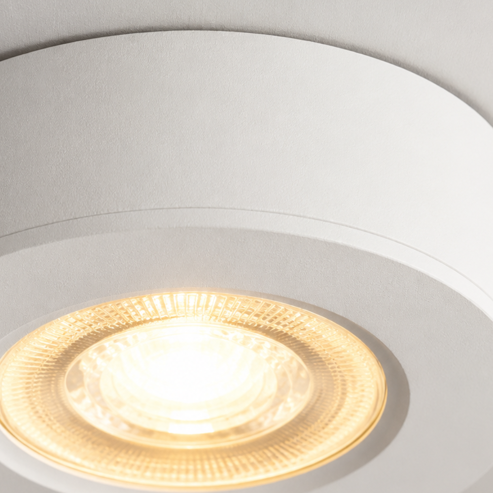Close-up of an ultra-thin round white LED ceiling light glowing warm white.