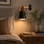 Wall sconce illuminated in a bedroom setting, casting downward light beside the bed.
