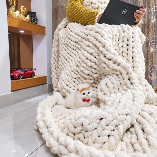 Cream white chunky chenille throw blanket draped over a seated laptop user